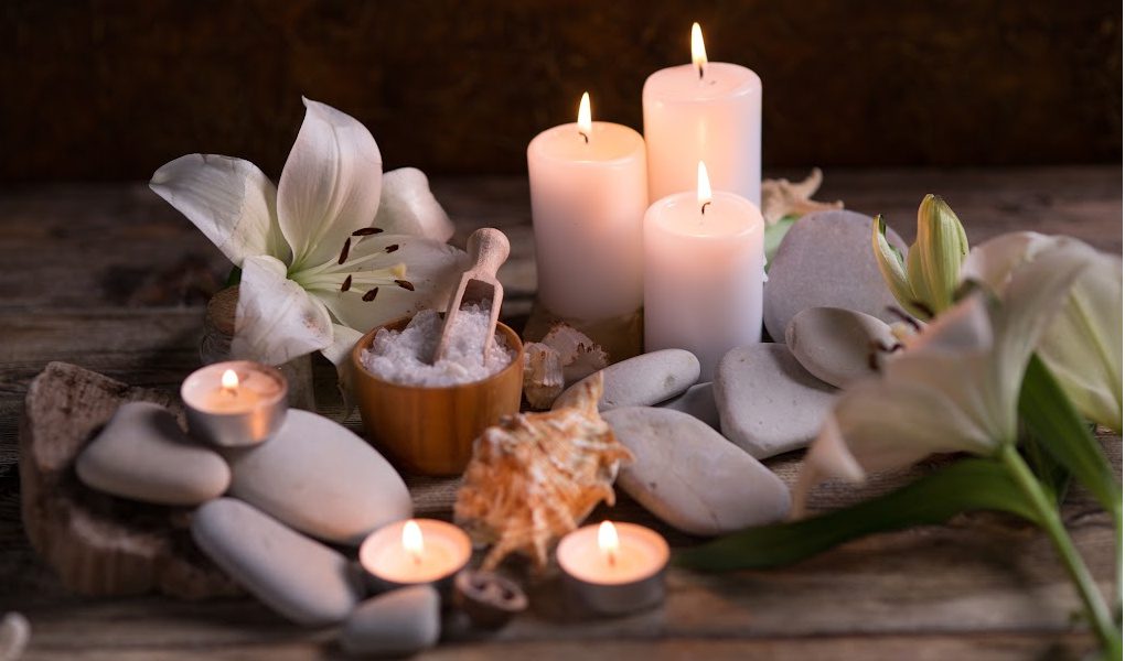 Zen-like photo of spa candles, flowers, massage stones and candles