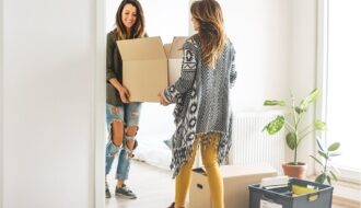 Mother and young adult daughter moving boxes into new apartment