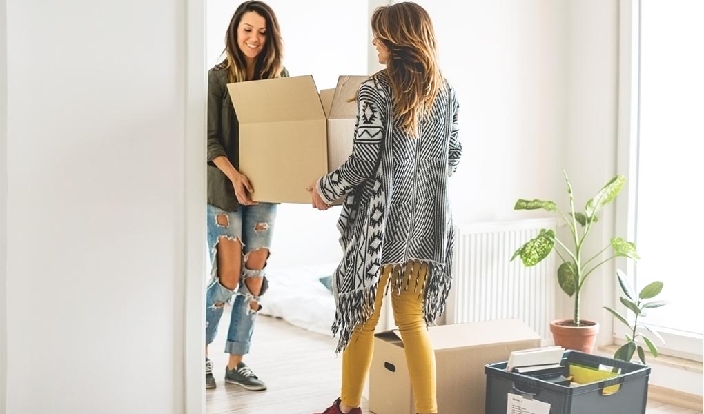 Mother and young adult daughter moving boxes into new apartment